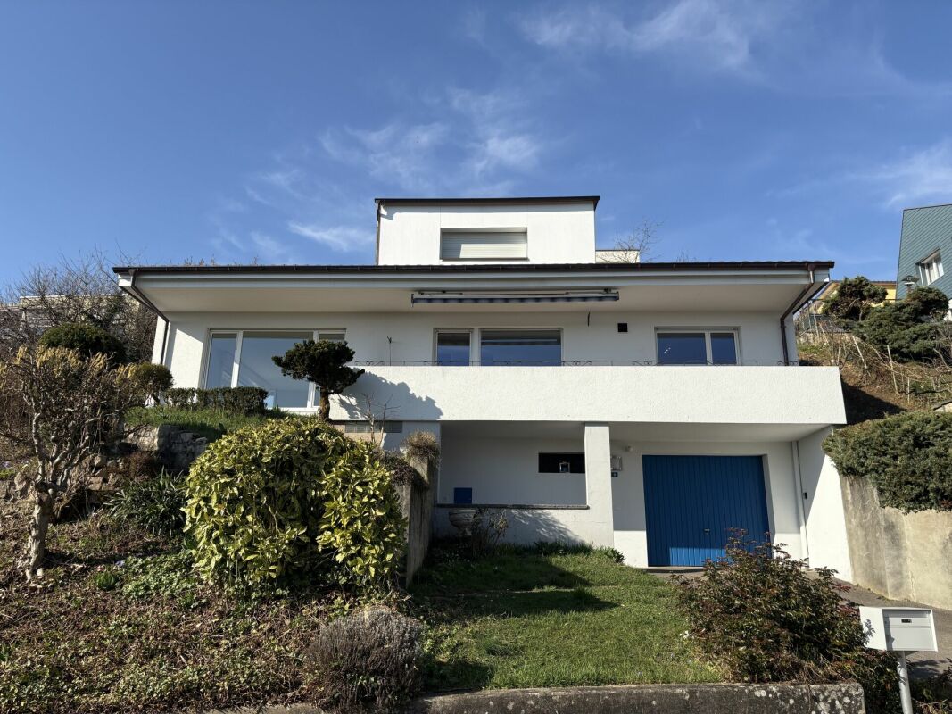 Modernes Einfamilienhaus mit Balkon und blauer Garage