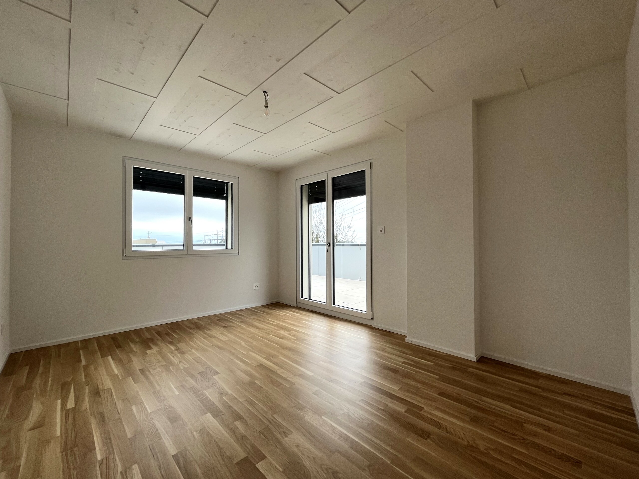 Leerer heller Raum mit Holzboden und Balkonzugang