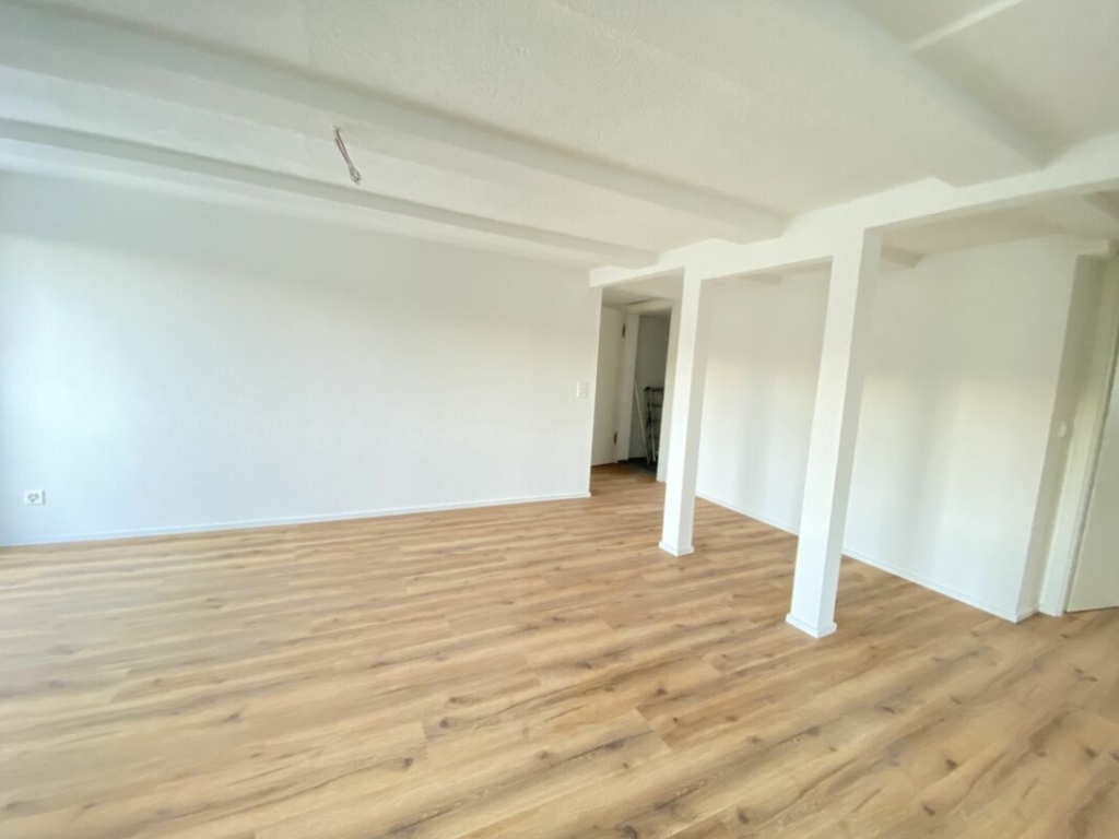 Leerer, renovierter Wohnraum mit Holzboden und weißen Wänden