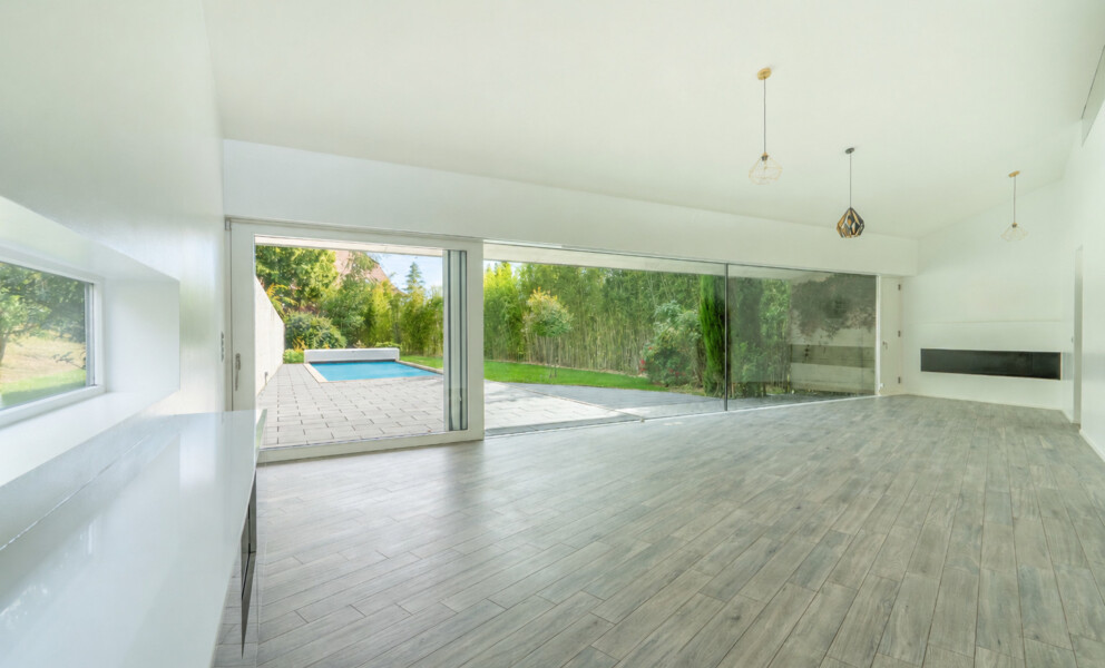 Offener Wohnraum mit Blick in den Garten und zum Pool