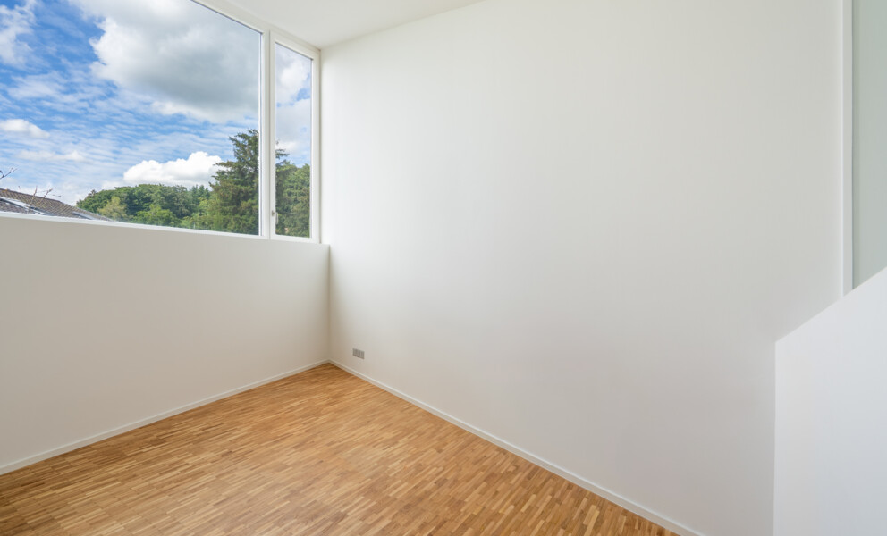 Heller leerer Raum mit großem Fenster und Holzfußboden