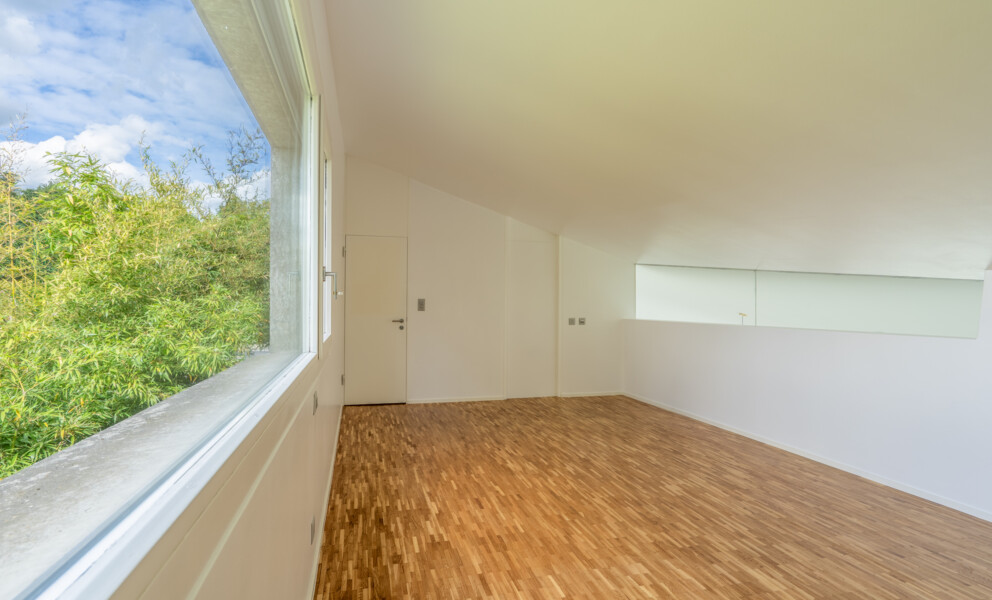 Heller leerer Innenraum mit großem Fenster und Holzfußboden