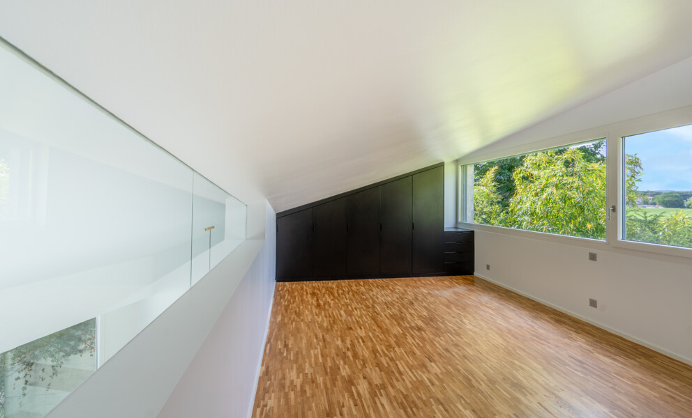 Dachgeschossraum mit großen Fenstern und Einbauschrank
