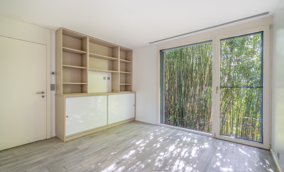 Helles Zimmer mit Schrankwand und großer Schiebetür zum Grünen