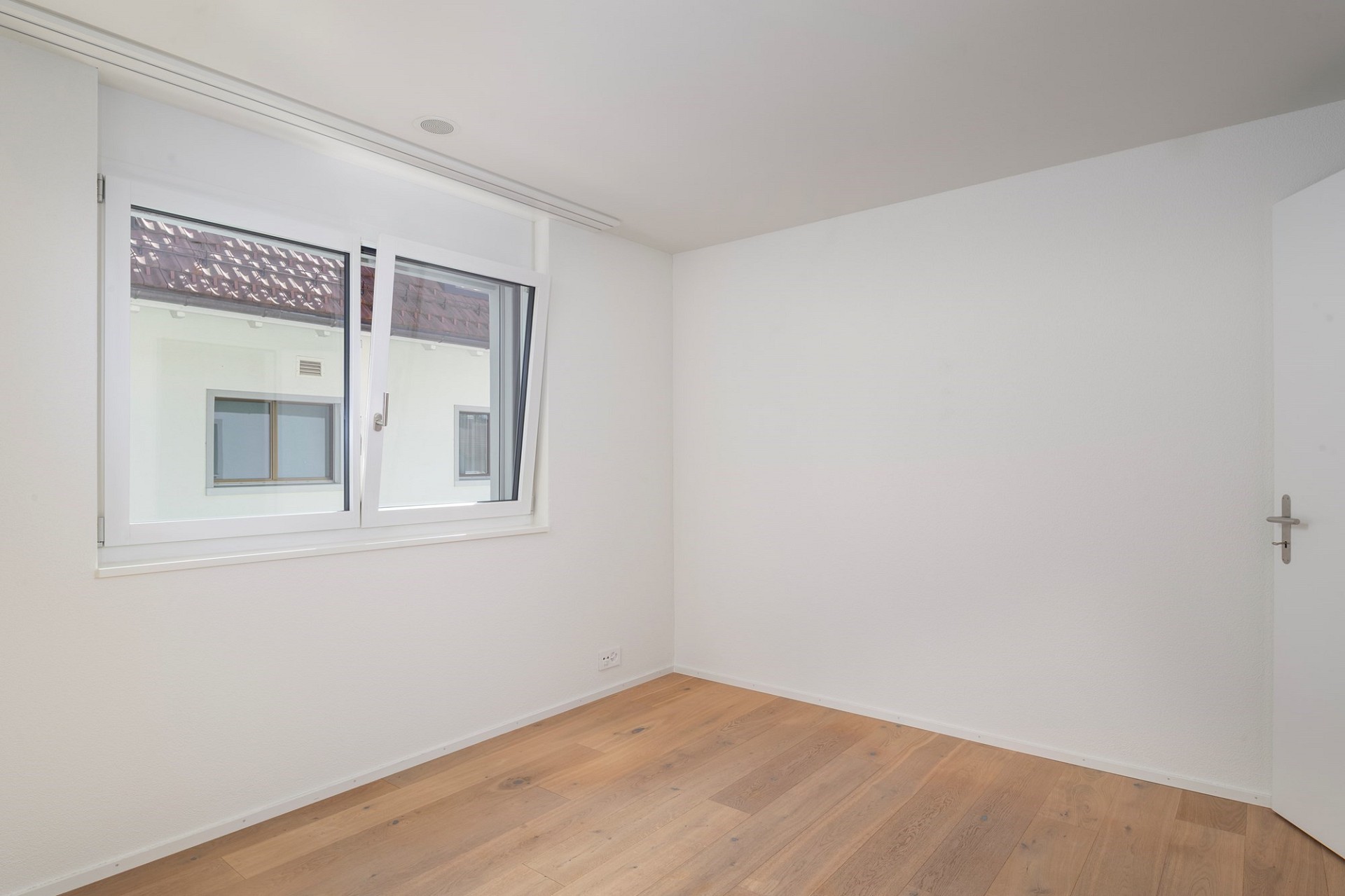 Heller leerer Raum mit Fenster und Holzboden