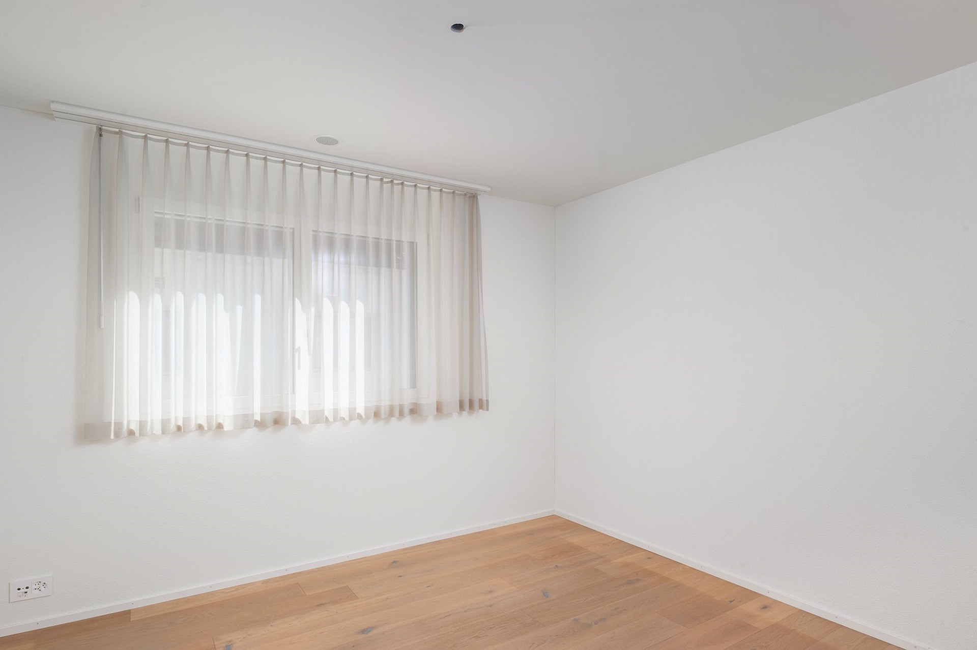 Heller leerer Raum mit Fenster und Vorhang