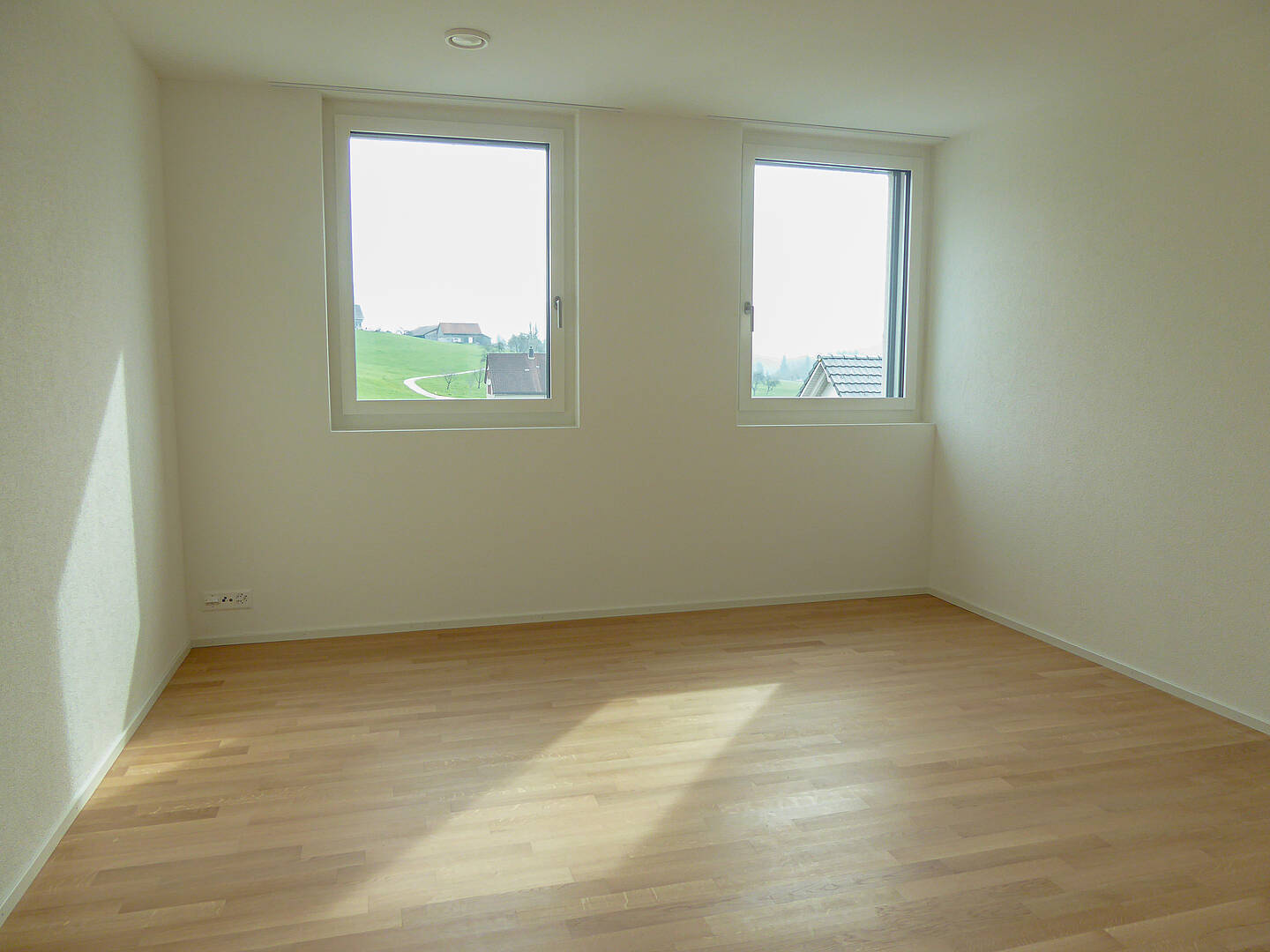 Leeres, helles Zimmer mit zwei Fenstern