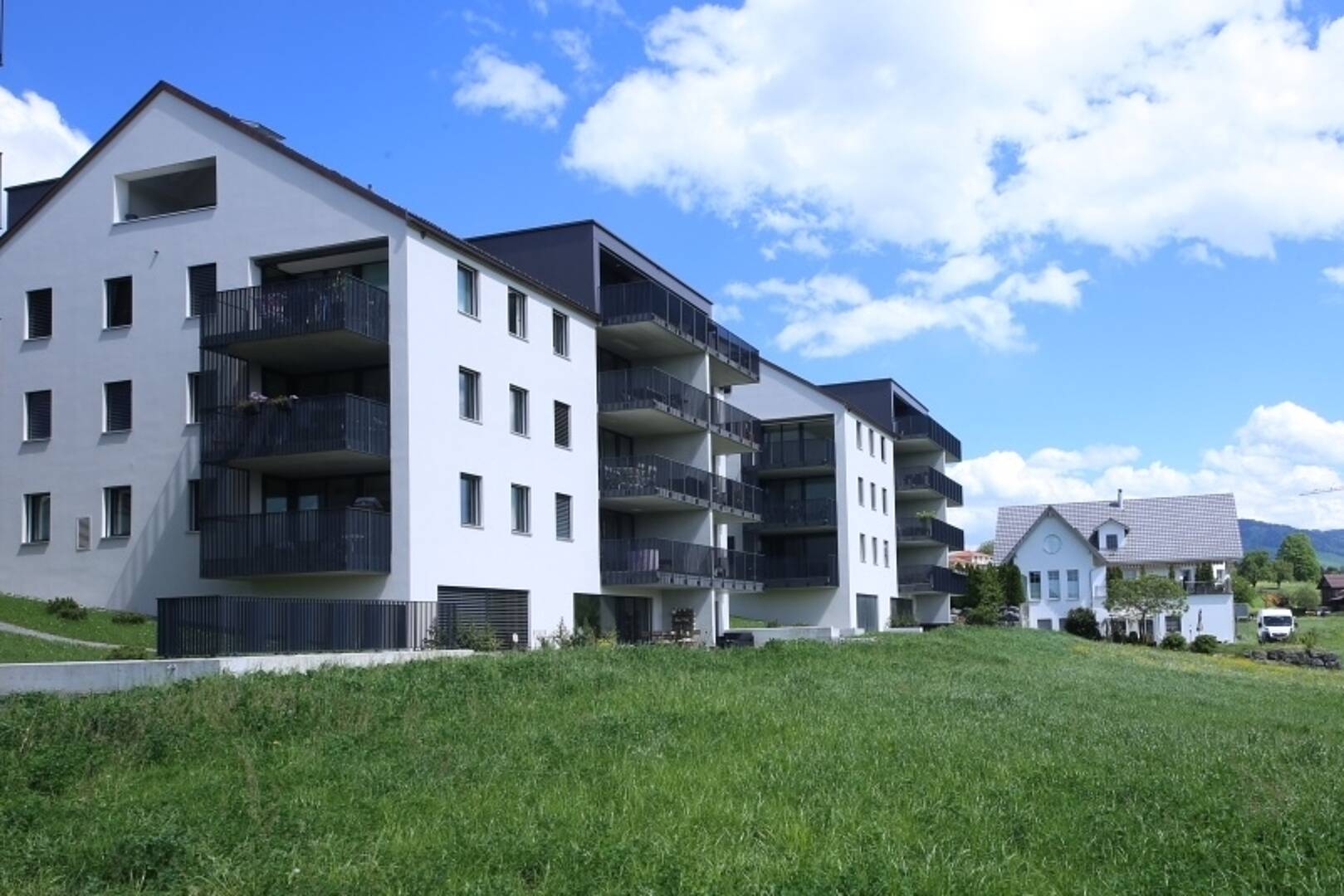 Mehrfamilienhaus mit Balkonen in grüner Umgebung