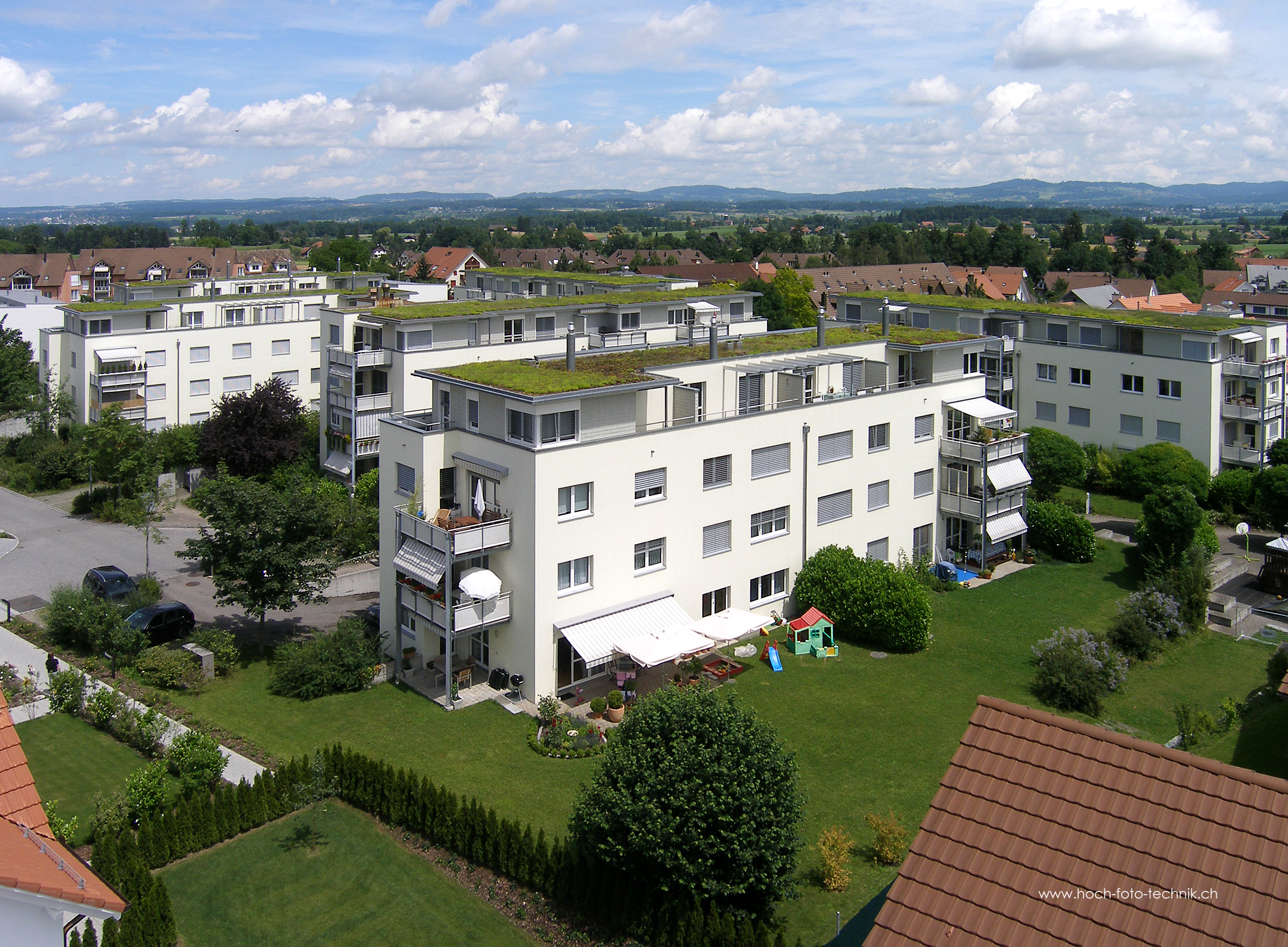 Wohnanlage mit begrünten Flachdächern und Gartenblick