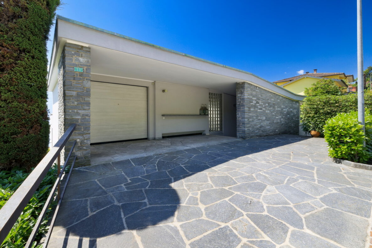 Moderner Hauseingang mit Carport und gepflasterter Zufahrt