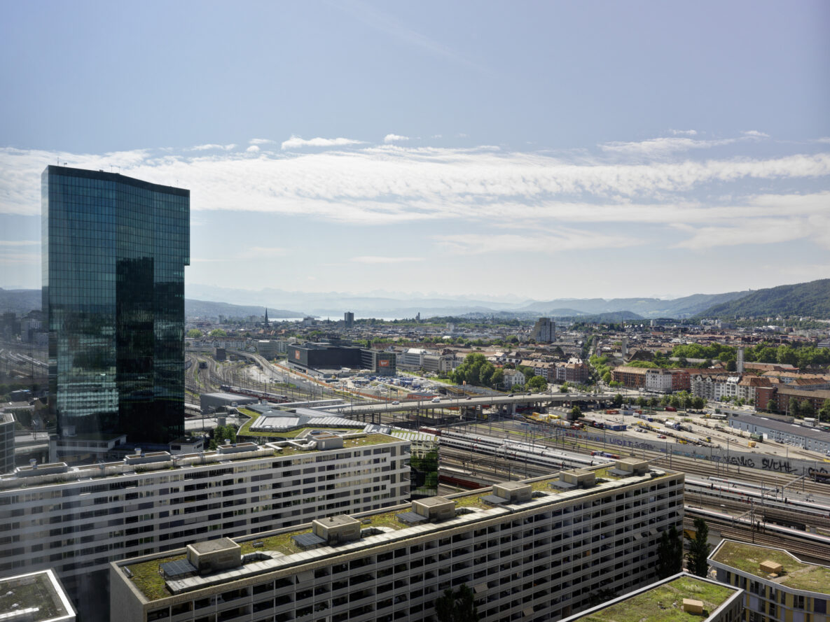 Städtischer Panoramablick mit Hochhaus und Bahnareal