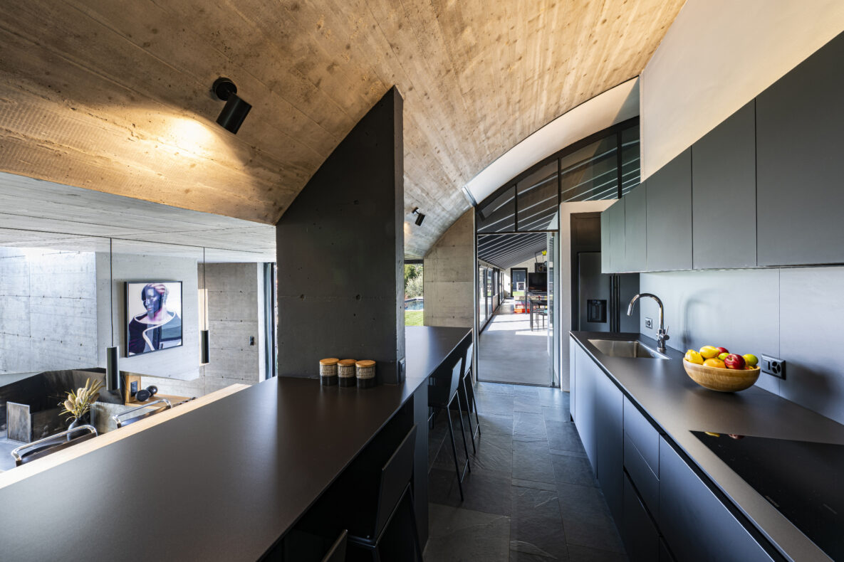 Moderne Küchen- und Wohnbereichsansicht mit Sichtbeton und dunkler Einbauküche
