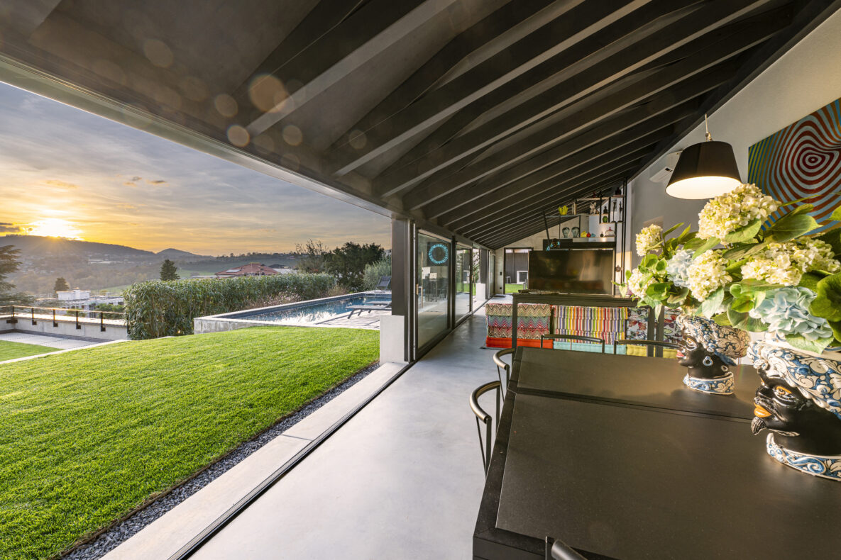 Überdachte Terrasse mit Poolblick bei Sonnenuntergang