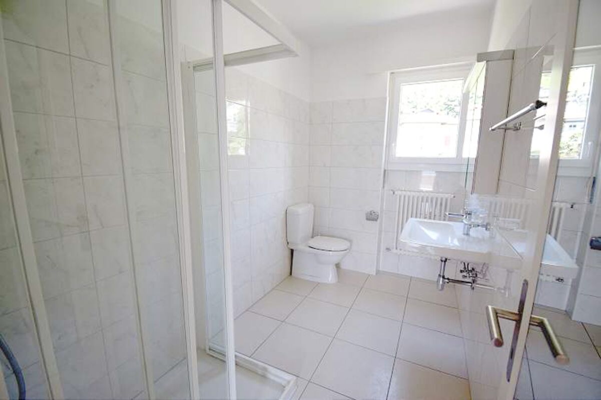 Helles, schlichtes Badezimmer mit Dusche, WC und Waschbecken