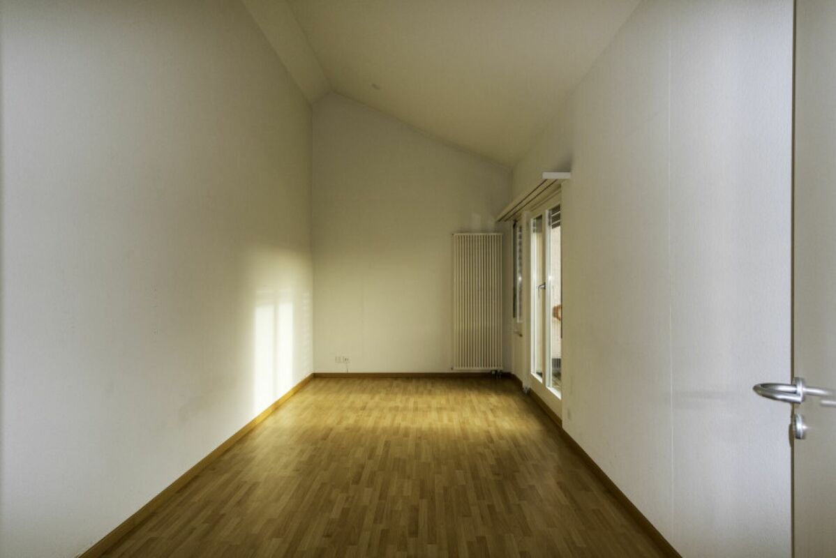 Leerer, heller Dachraum mit Holzboden und Fensterfront