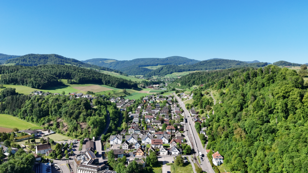 Luftaufnahme eines Tals mit Ortschaft und Bergen