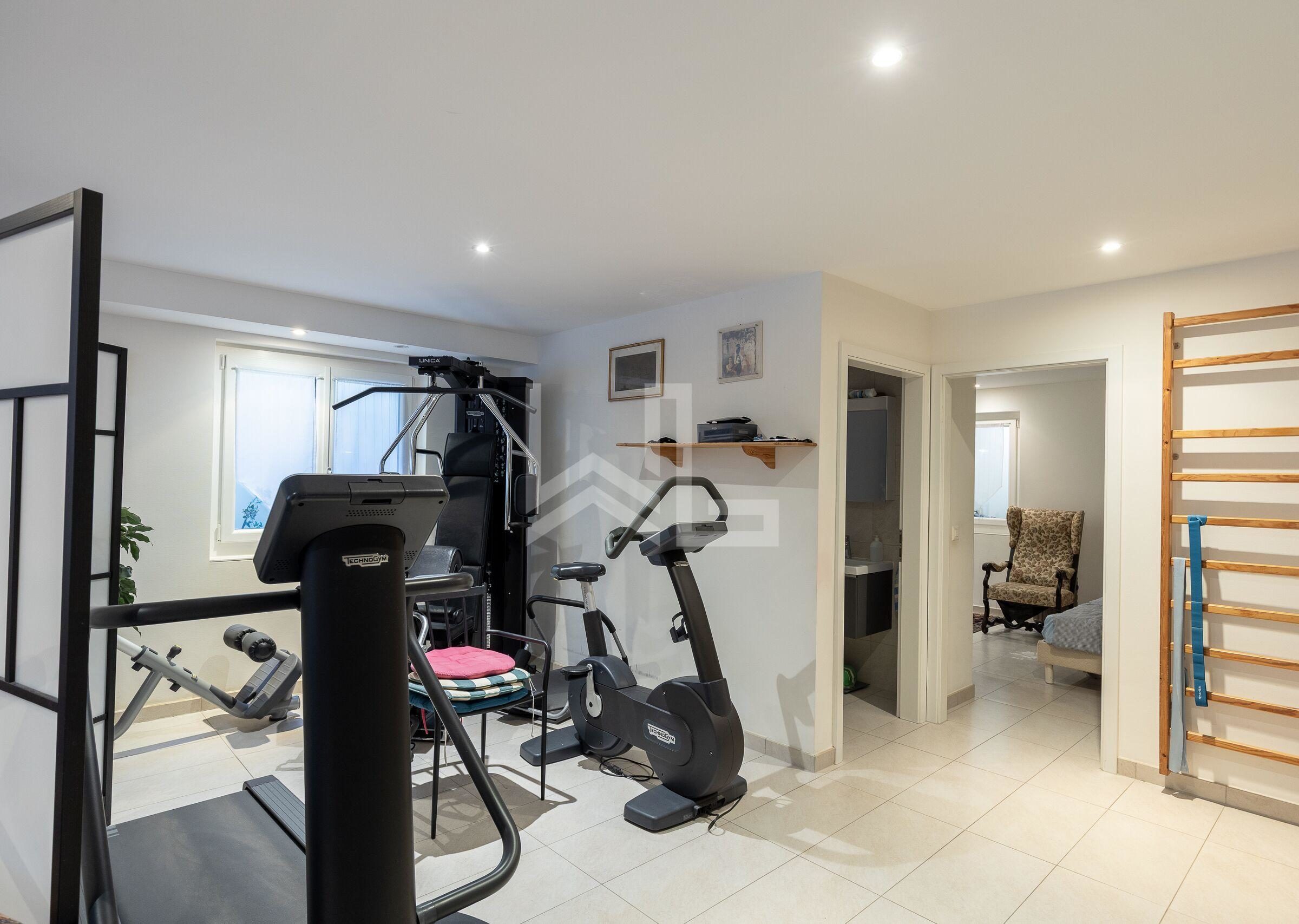 Fitnessraum mit Trainingsgeräten und angrenzenden Türen