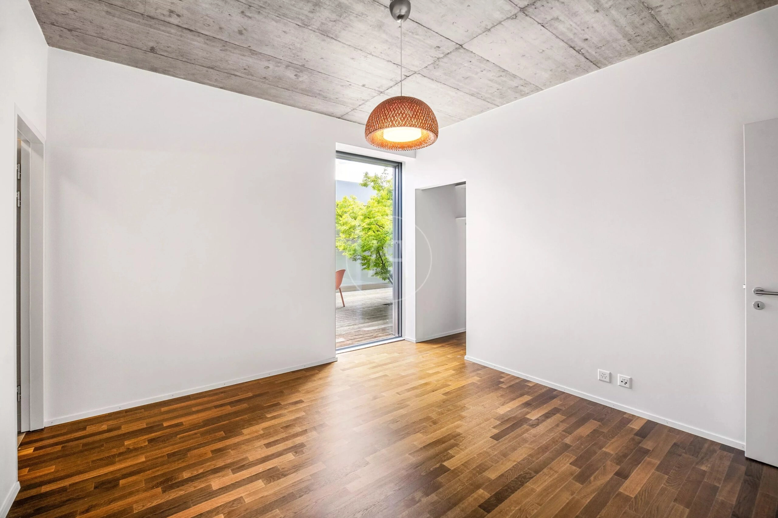 Modernes, leeres Zimmer mit Parkettboden und Beton-Decke