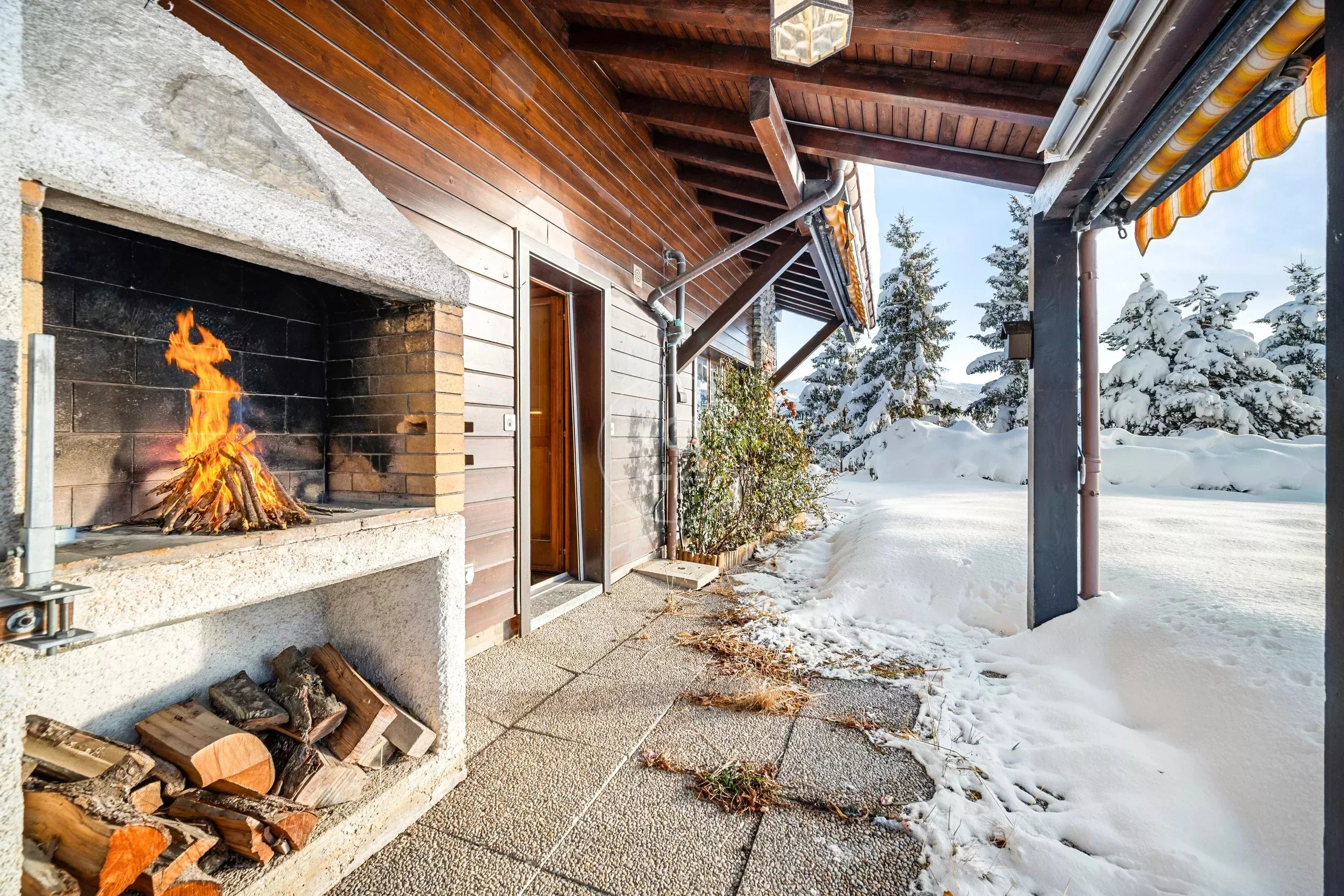 Überdachte Terrasse mit Kamin und verschneitem Außenbereich