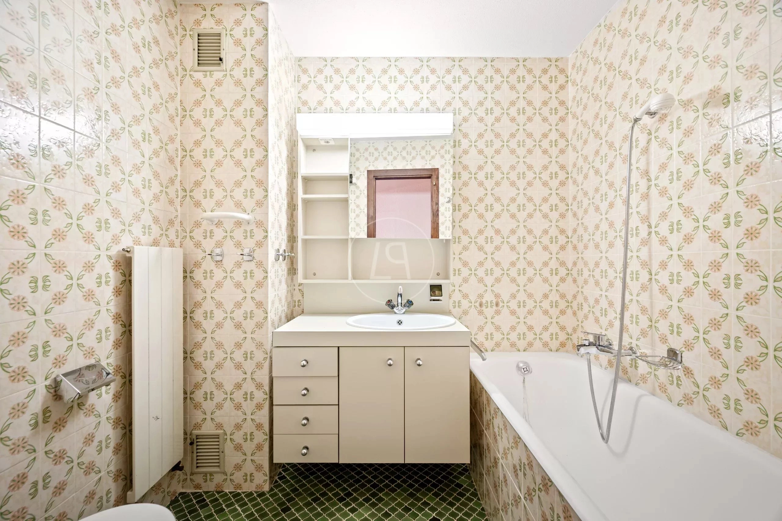 Kleines Badezimmer mit Badewanne und floralem Fliesendekor