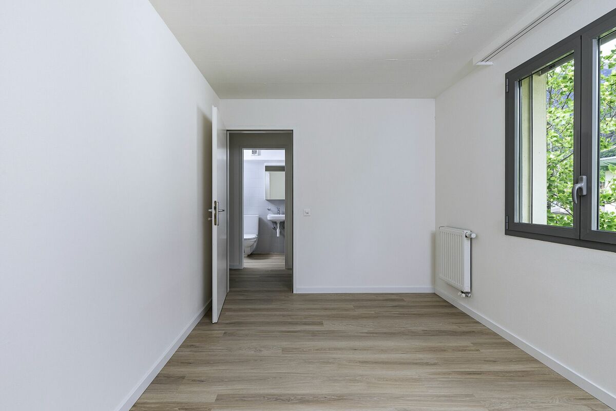 Heller, leerer Raum mit Blick in ein Badezimmer