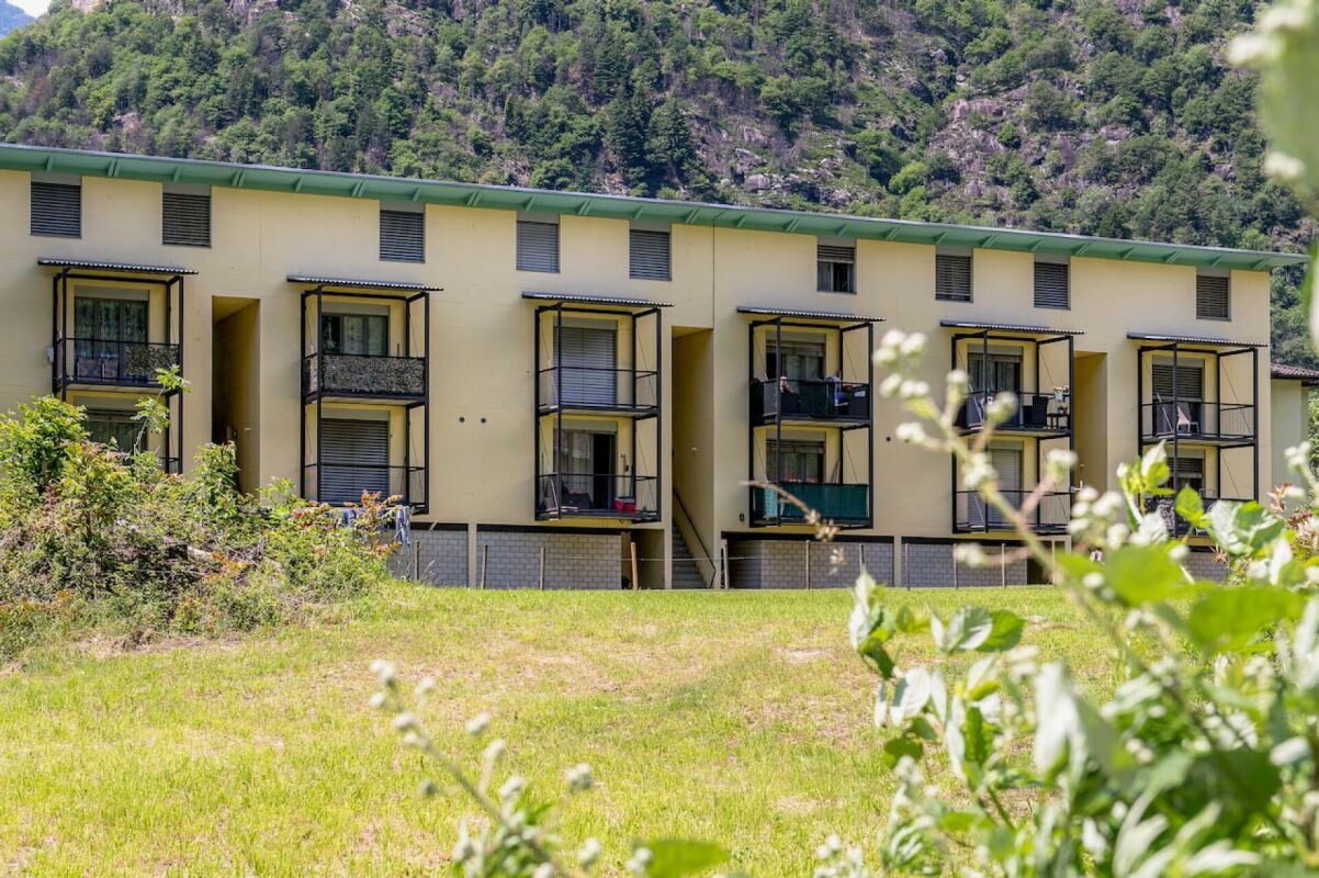 Mehrfamilienhaus mit Balkonen vor Bergkulisse