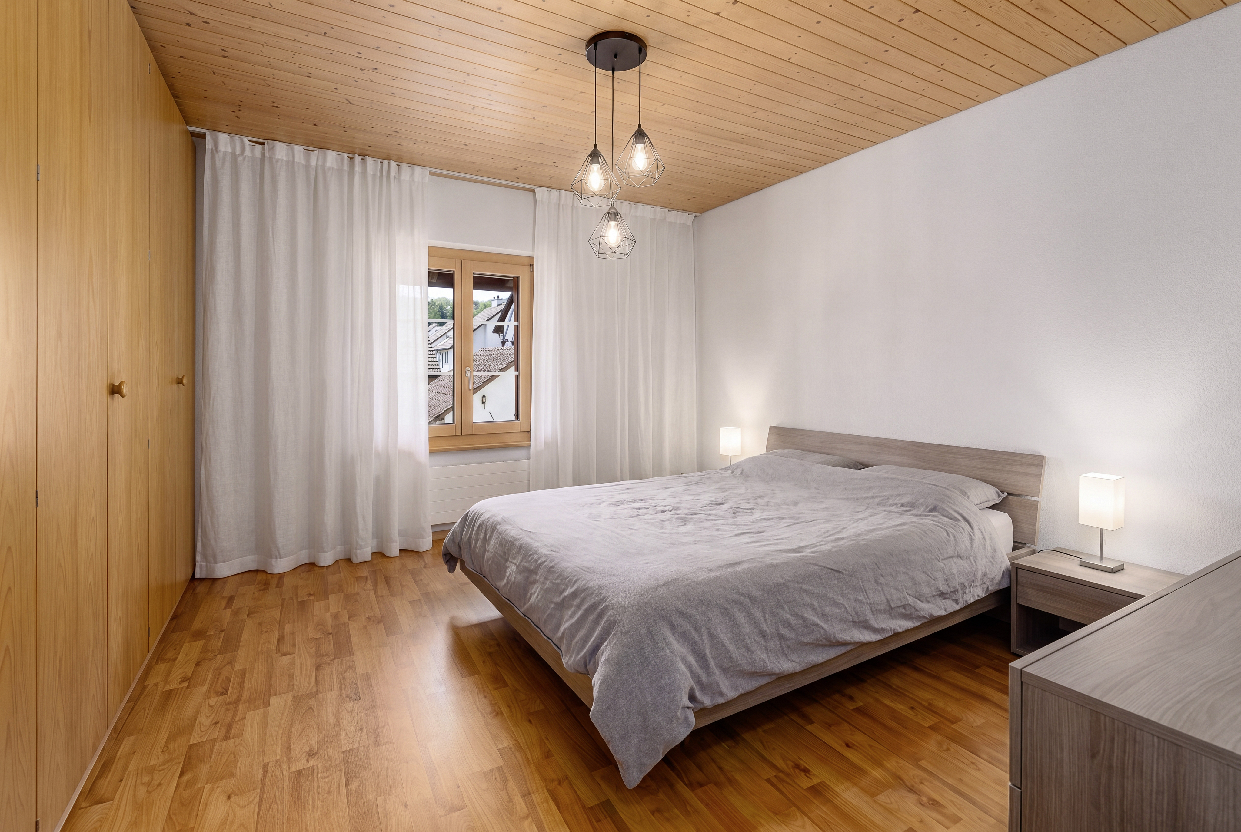 Helles Schlafzimmer mit Holzdecke und Blick ins Freie