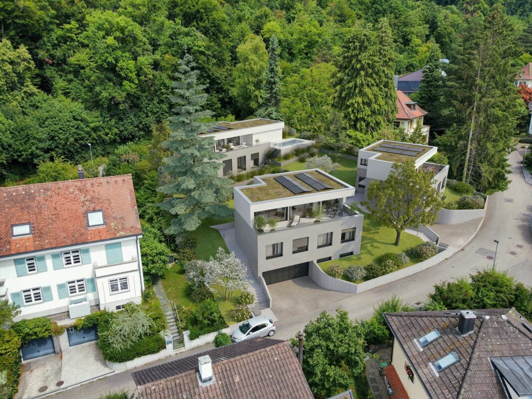 Moderne Wohnhäuser mit Solardächern in grüner Hanglage