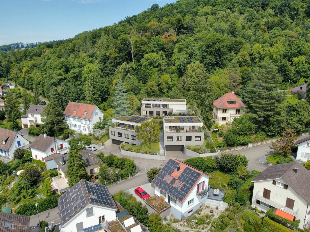 Luftaufnahme einer Wohnsiedlung am bewaldeten Hang