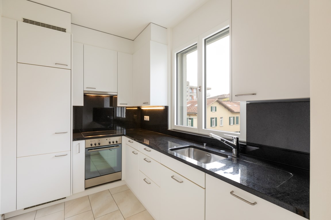 Moderne weiße Einbauküche mit schwarzer Arbeitsfläche