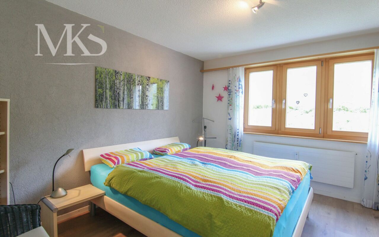 Helles Schlafzimmer mit Holzfenster und farbigem Bett