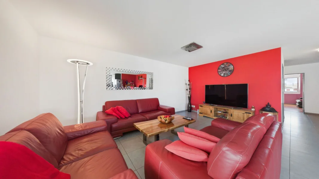 Wohnzimmer mit roten Sofas und TV-Wand