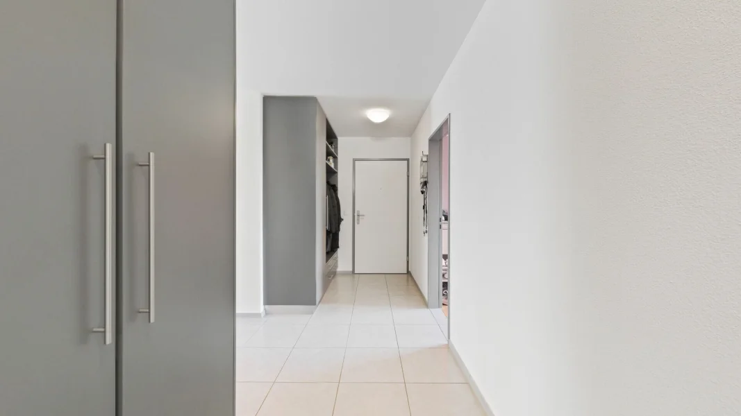 Flur mit Einbauschrank und weißen Fliesen