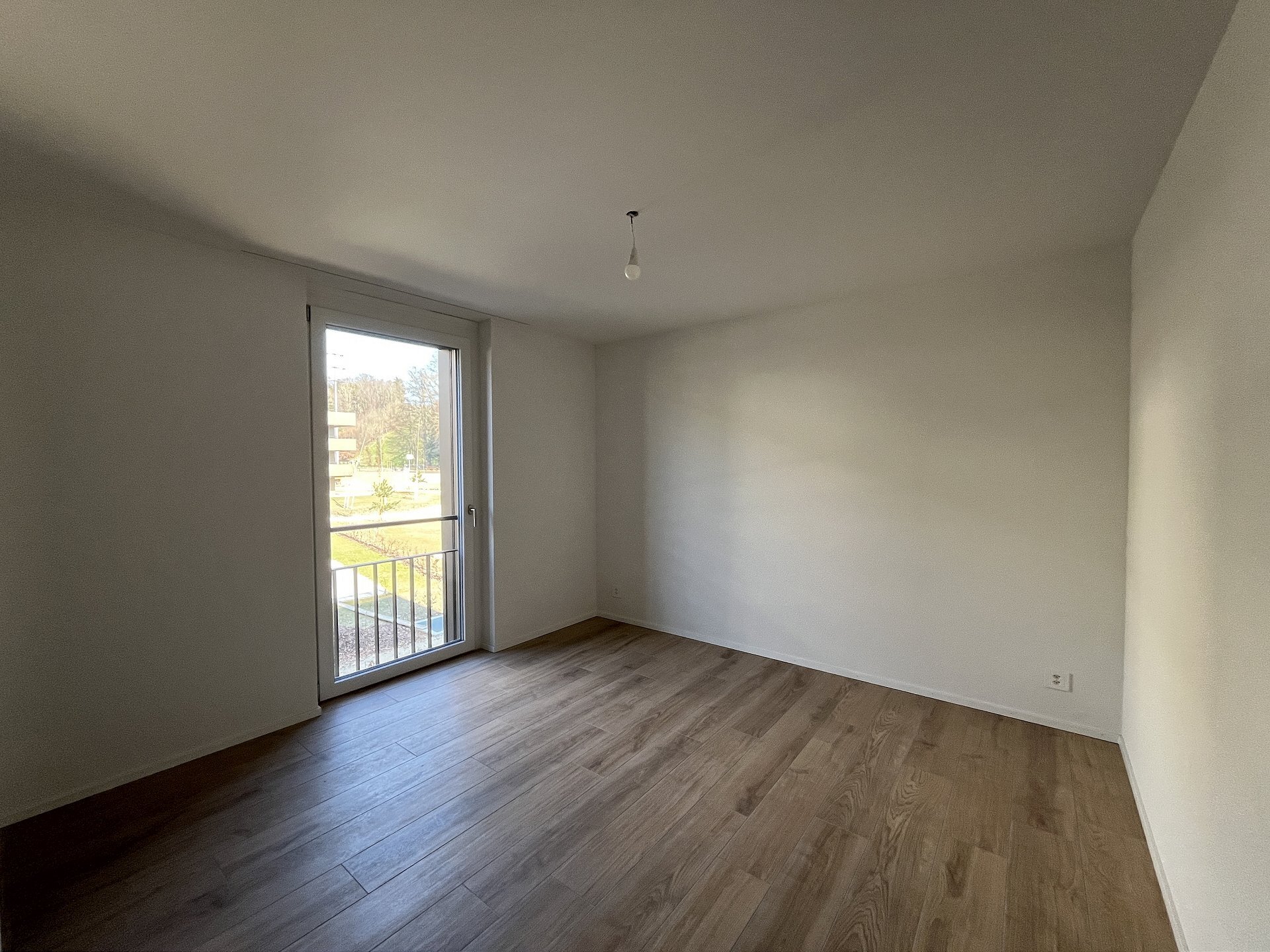 Leeres, modern geschnittenes Zimmer mit Balkon-/Terrassentür