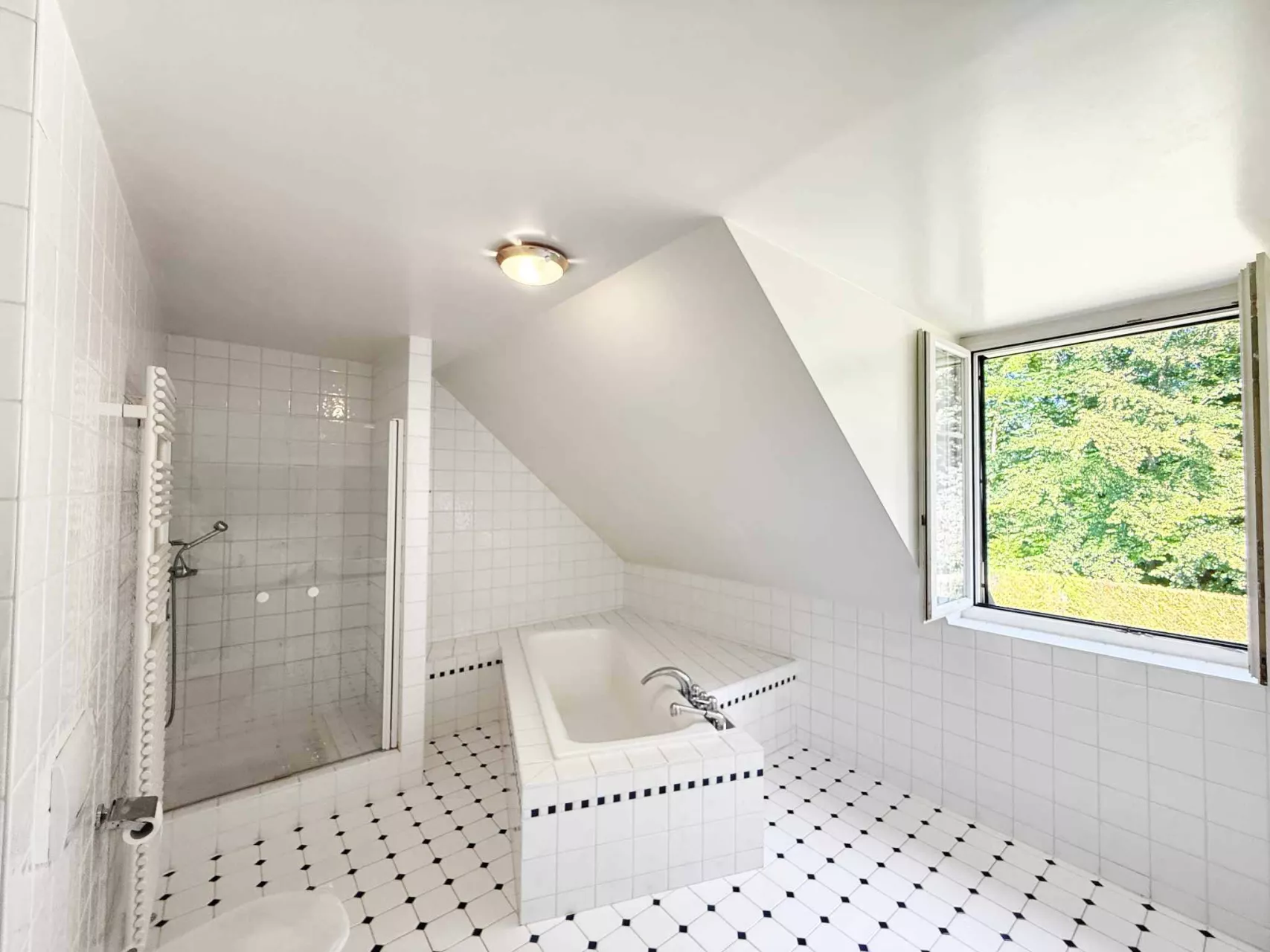 Helles Badezimmer mit Badewanne und Dusche unter Dachschräge