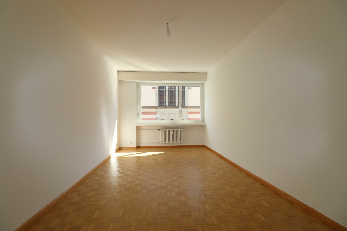 Leerer, schmaler Wohnraum mit Fenster und Heizkörper