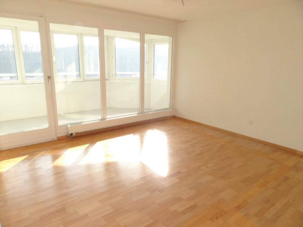 Leeres, sonnendurchflutetes Zimmer mit Balkonfenstern