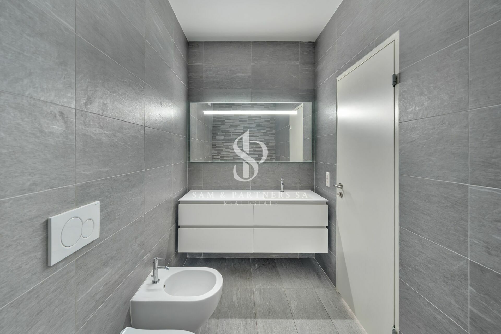 Modernes Badezimmer mit grauen Wandfliesen und weißem Waschtisch