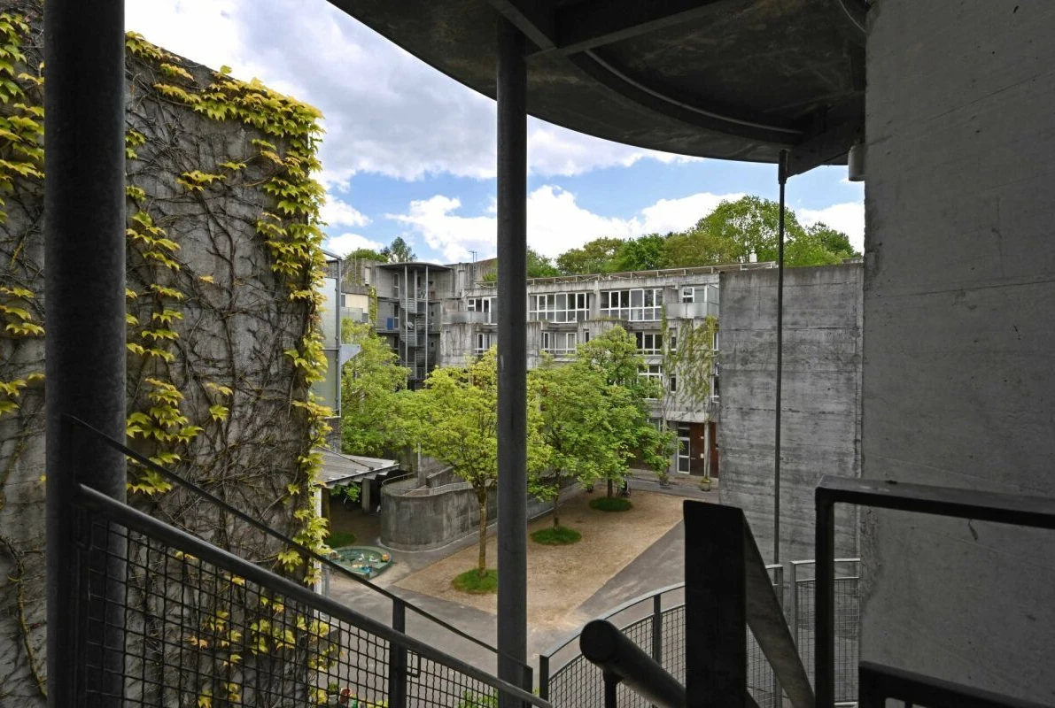 Blick in einen begrünten Innenhof von einem Balkon oder Treppenpodest