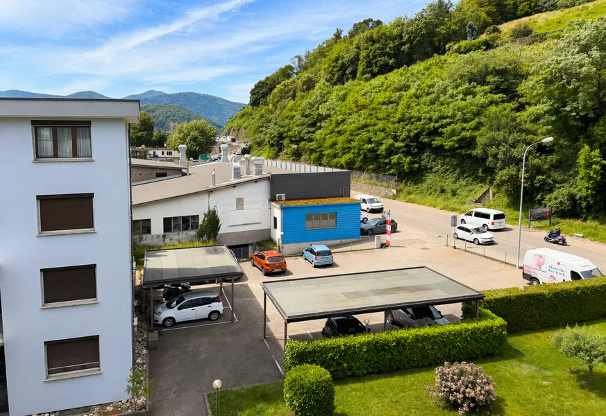 Blick auf Wohngebäude und Parkplatz in grüner Hanglage