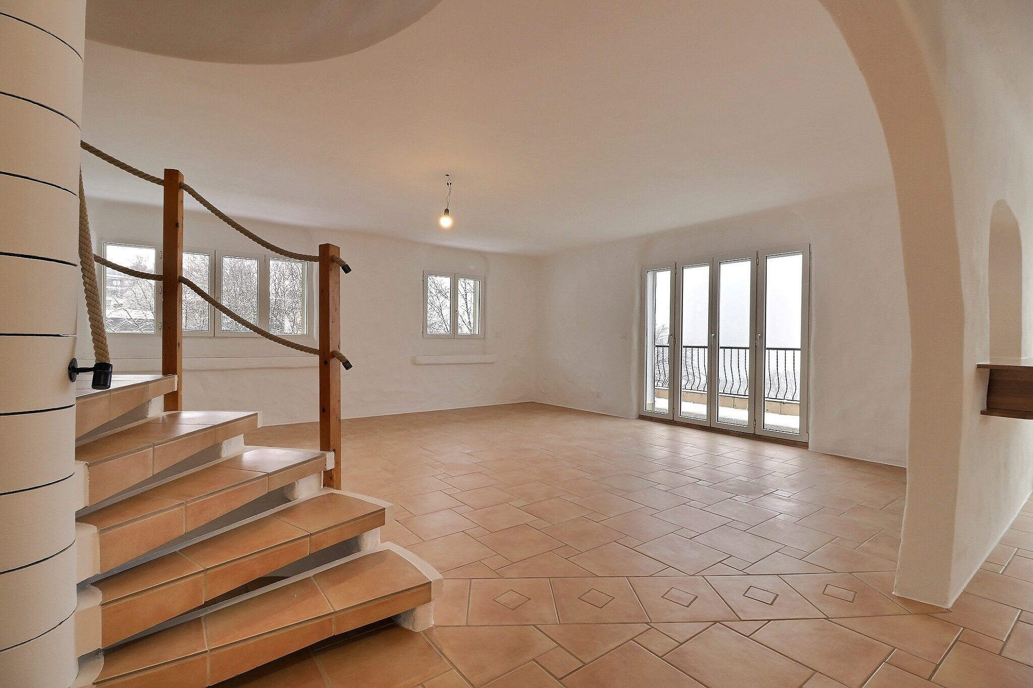 Heller Wohnraum mit Treppe und Balkonfenstern
