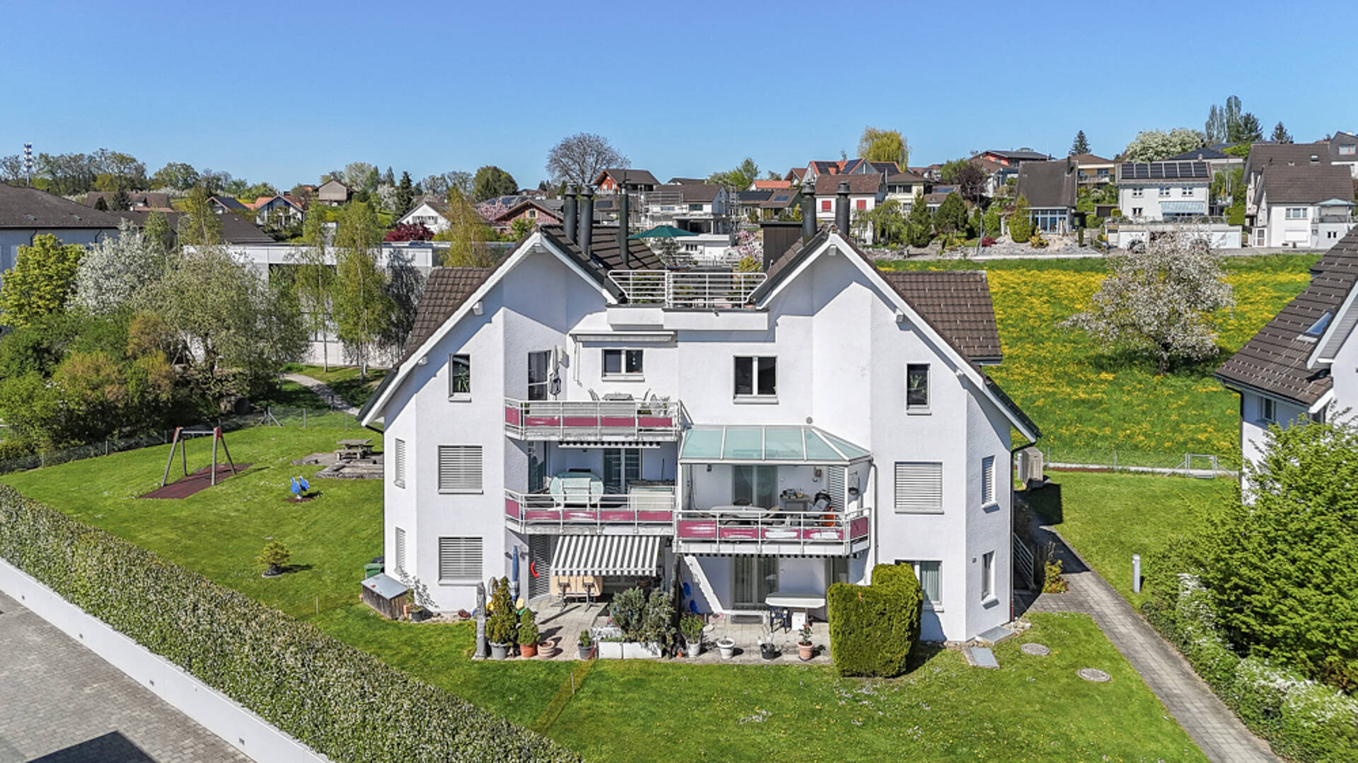 Außenansicht eines Einfamilienhauses mit Gärten und Balkonen