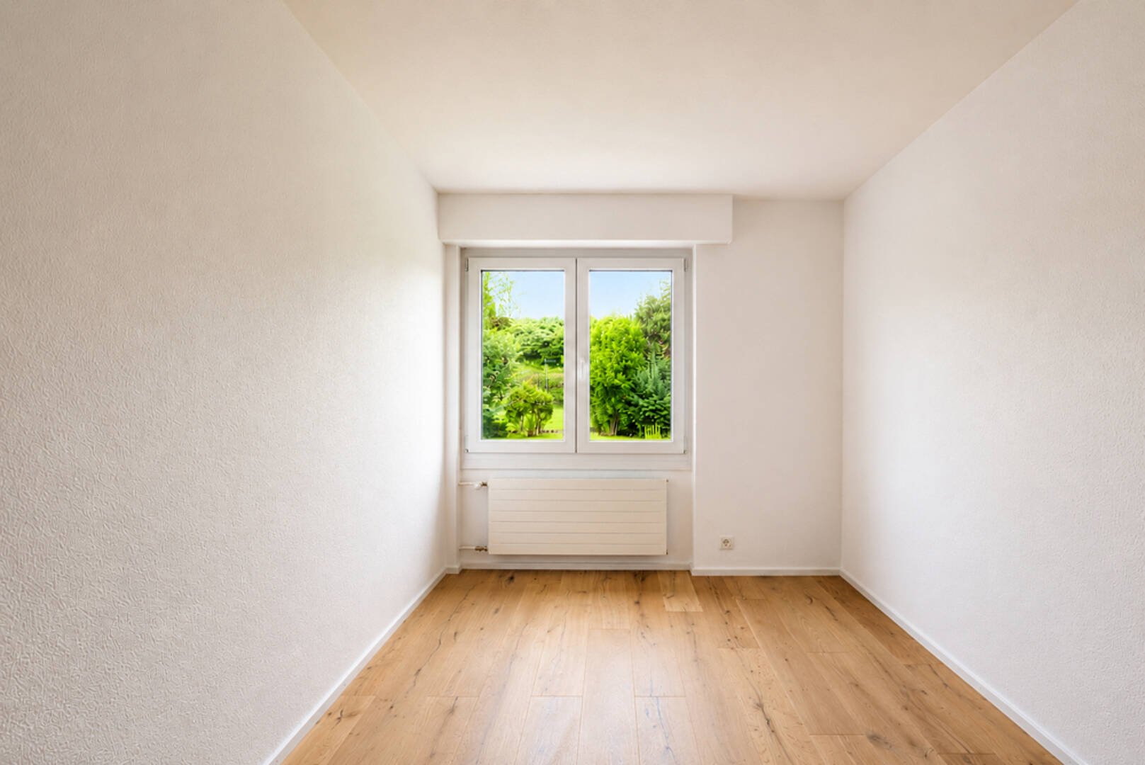 Leerer heller Raum mit Fenster und Parkettboden