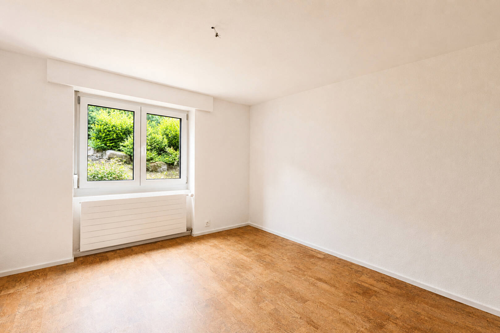 Leeres, helles Zimmer mit Fenster und Heizkörper