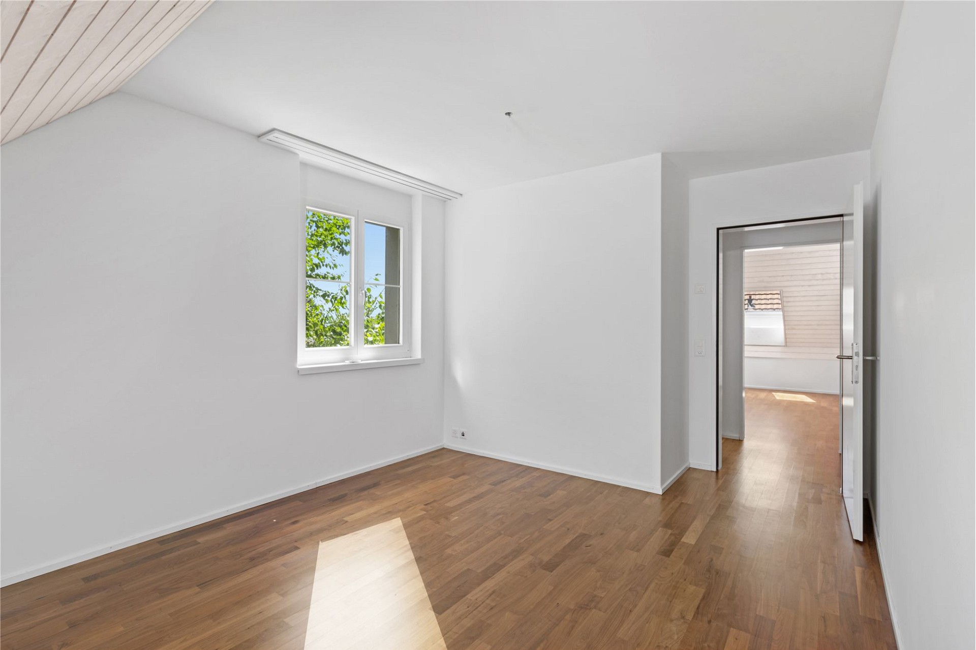Heller leerer Raum mit Holzboden und Fenster