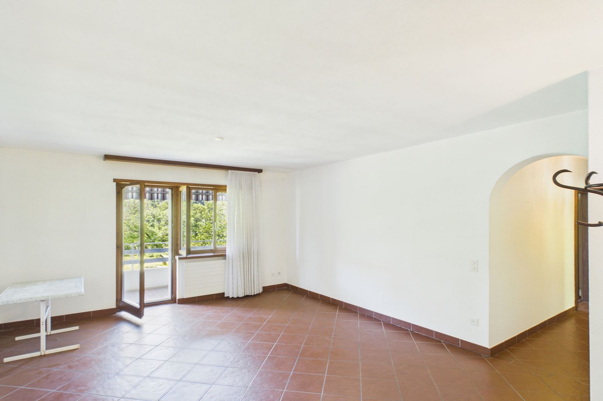 Heller leerer Wohnraum mit Terrassentür und Balkonblick