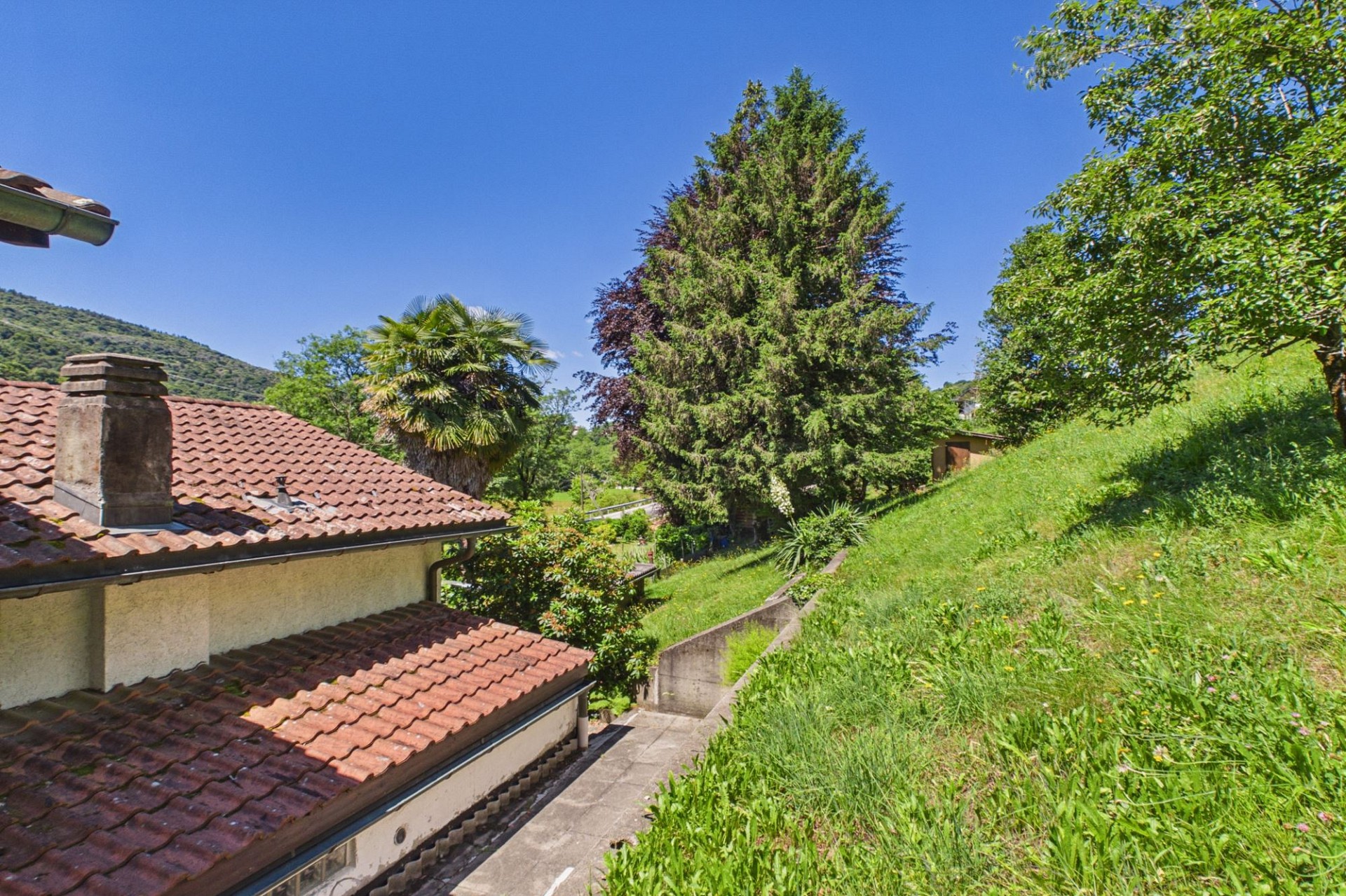 Gartenhang mit Hausdach und Ausblick ins Grüne