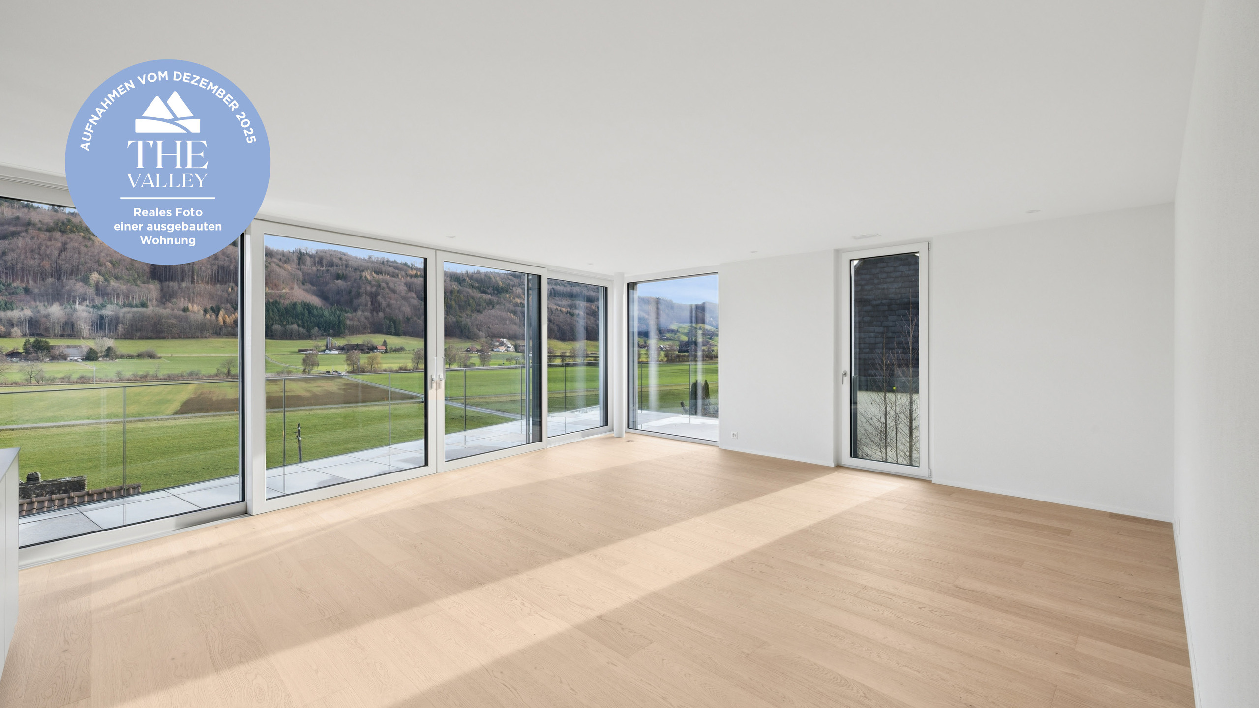 Heller Wohnraum mit Panoramafenstern und Alpenblick