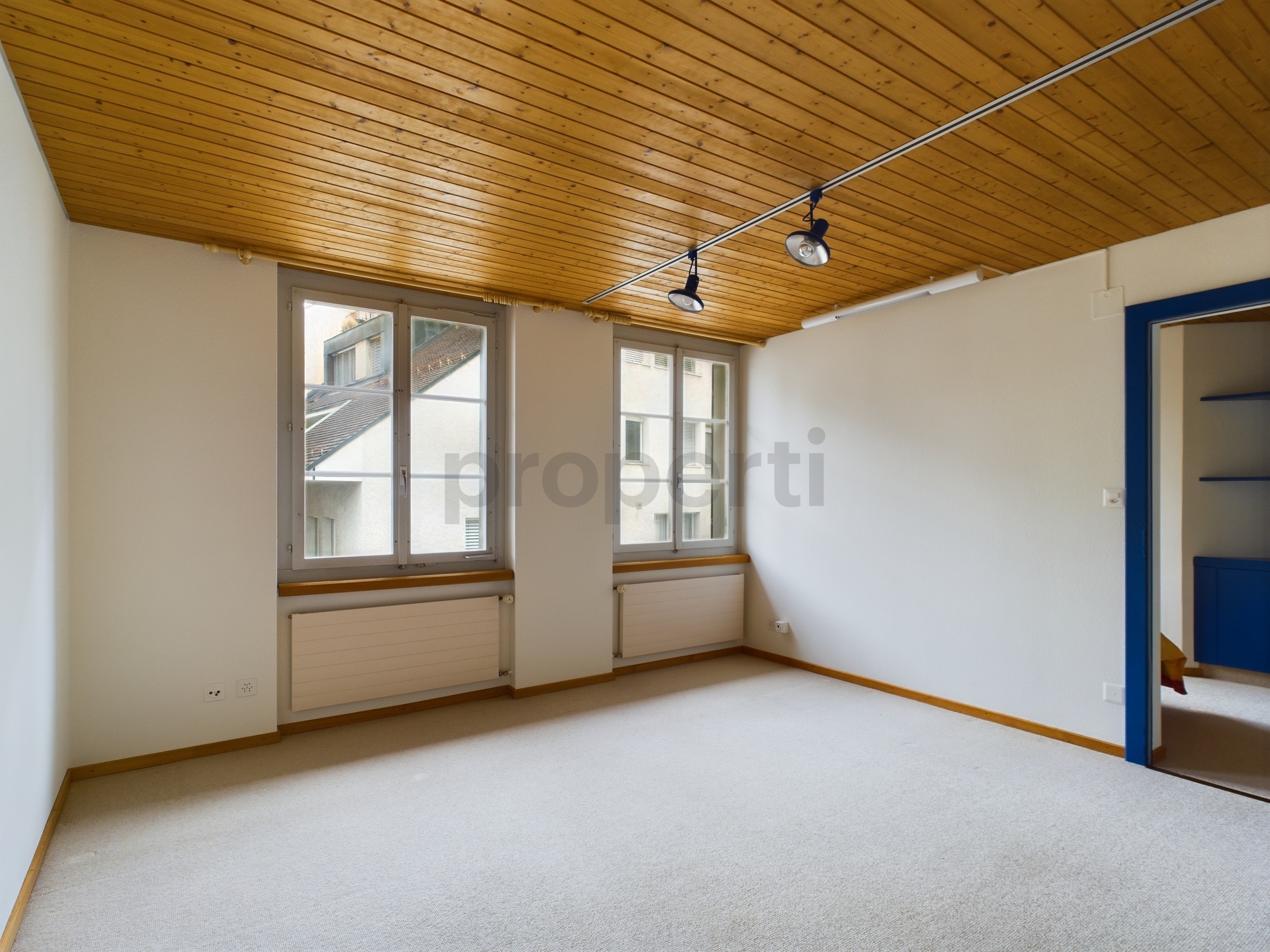 Heller leerer Raum mit Holzdecke und Teppichboden