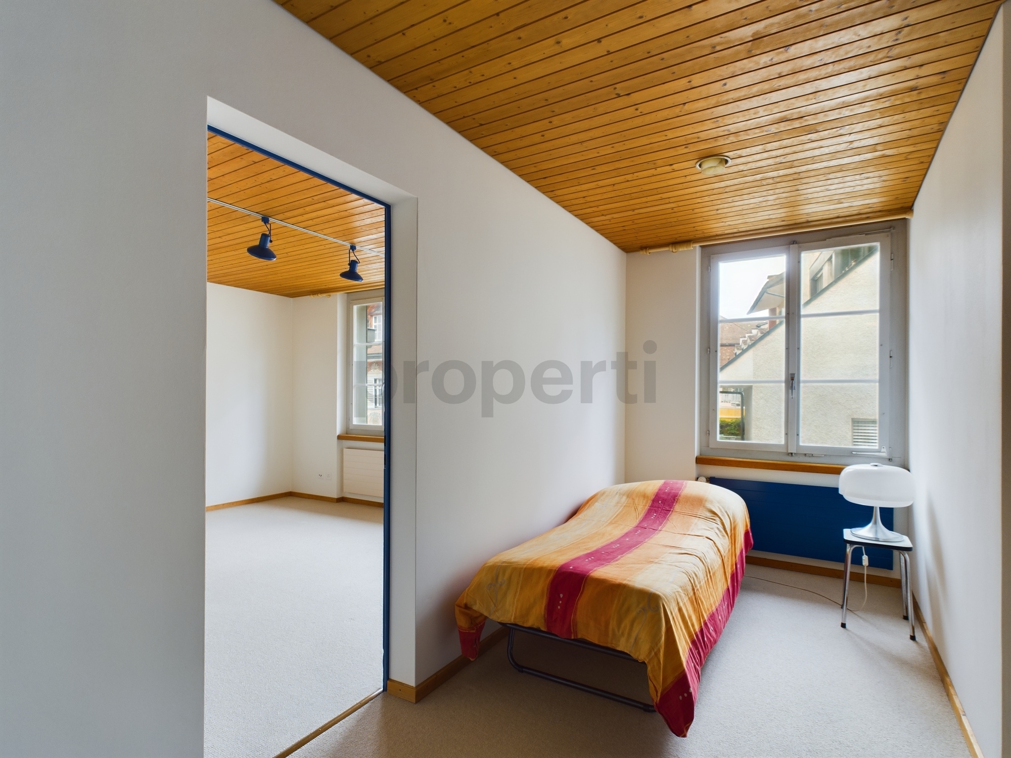 Ein schmales Schlafzimmer mit Bett und Fensterblick